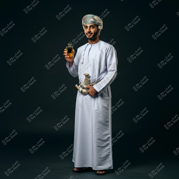 The image shows a man dressed in traditional Omani attire, including a white dishdasha and an Omani turban. He is holding a perfume bottle in his hand, with a traditional Omani dagger at his waist. The background is dark.