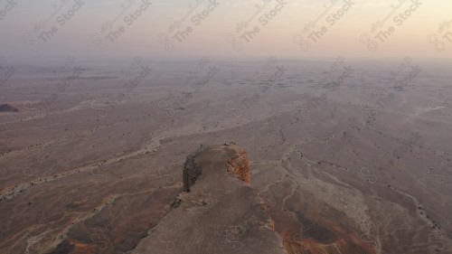 لقطة جوية لمجموعة سياح على جبل من جبال طويق المسمى بحافة العالم. سلسلة من الجبال الصخرية