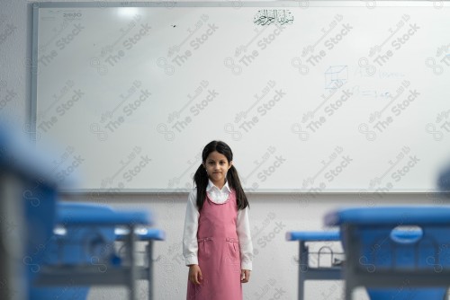 A Saudi student wears a school uniform and does different interactions and shows the tables in the classroom