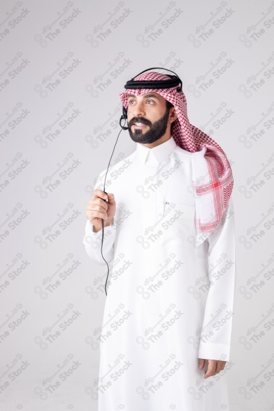 بورتريه رجل سعودي يلبس سماعة الرأس ويقوم بالتواصل عبر السماعة - خدمة العملاء ، مكالمة هاتفية