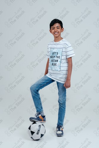 Smiling Saudi boy holding a soccer ball on a white background, a soccer game