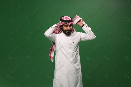 بورتريه رجل سعودي يرتدي الزي السعودي التقليدي يعدل شماغه