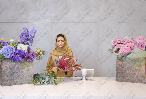 A Saudi woman wearing an abaya working in a flower shop, a bouquet of roses. Holidays and occasions, happy occasions, surprise, Christmas