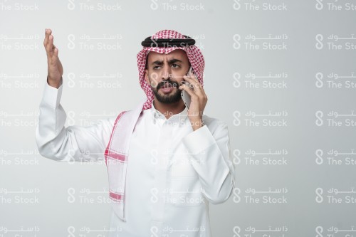 رجل سعودي يقوم بإشارات وهو يتحدث على الهاتف