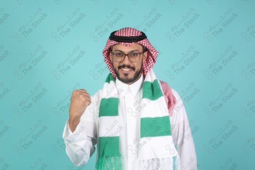 شاب سعودي يرتدي الزي السعودية ممسك شال بيده يقوم بتعابير وجه و يدين تدل على السعادة والحماس ، كأس العالم ، المنتخب السعودي.