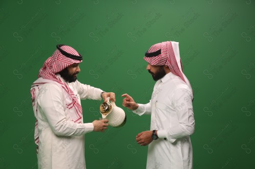 رجل سعودي يرتدي الزي السعودي التقليدي يقدم لضيفه القهوة السعودية في أحد المناسبات