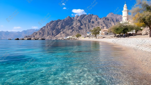 The image depicts a beach with clear blue water reflecting sunlight. In the background, there is a rugged mountain range under a clear blue sky. An Islamic architectural building with a tall minaret is visible. The beach is adorned with some green trees and simple houses lining the coast.