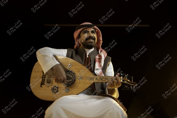 رجل يرتدي ثوبًا عربيًا تقليديًا ويعزف على العود بابتسامة.