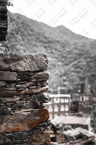 An ancient building built of stones in the middle of a group of windows surrounded by white paint while the sky looks cloudy during sunset, Rijal Almaa Heritage Village in the Asir region