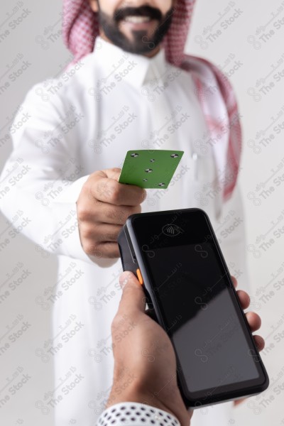 Portrait of a Saudi man holding a card and making automatic payments on a white background