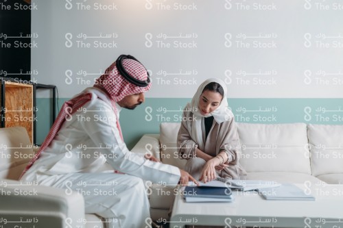 اجتماع بين رجل و امرأة سعوديان في مكتب، اجتماع عمل بين شاب سعودي وشابة سعودية في مكتب داخلي.