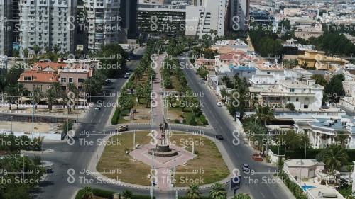 ممشى يتوسط الطريق محاطًا بالنخيل في مدينة جدة، المنازل والمباني بجدة نهارًا