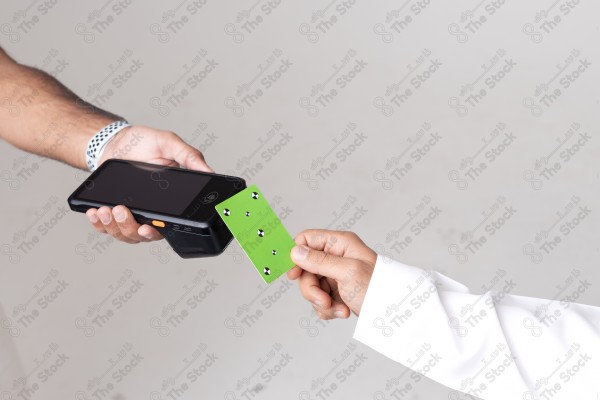 Portrait of a Saudi man holding a card and making automatic payments on a white background