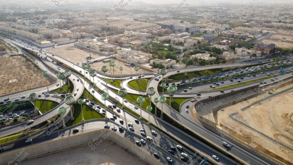 تصوير جوي لحركة سير السيارات على الطريق السريع في مدينة الرياض، الفن الهندسي المعماري للمجسمات الفنية على شكل أشجار خضراء، الطرق المتقاطعة في دوار عرقة بالمملكة العربية السعودية، البنية التحتية المتطورة