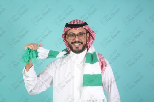 شاب سعودي يرتدي الزي السعودية ممسك شال بيده يقوم بتعابير وجه و يدين تدل على السعادة والحماس ، كأس العالم ، المنتخب السعودي.