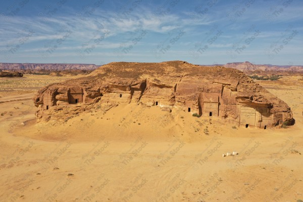 لقطة جوية بريه لبيوت منحوته داخل الجبال بمدائن صالح الحجر في العلا وتظهر السماء شبة غائمة، السياحة في السعودية ،جمال الطبيعه ، المعالم التاريخية في العلا