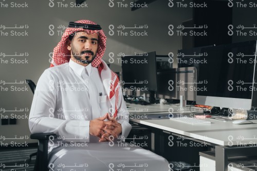 موظف سعودي يرتدي الثوب ويجلس في المكتب.