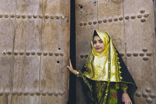 A snapshot of a girl standing in front of a wooden door wearing the Saudi traditional dress, the day of the foundation, a popular dress.