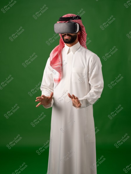 رجل يرتدي الزي التقليدي ويستخدم نظارة واقع افتراضي على خلفية خضراء.