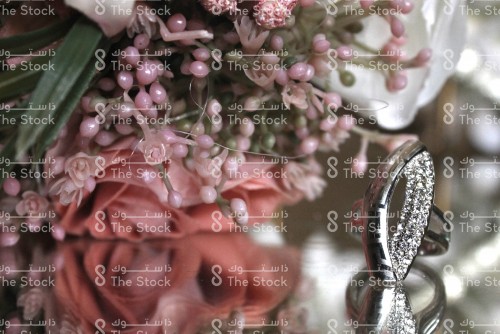 Wedding details of a ring, white roses and a bouquet of roses