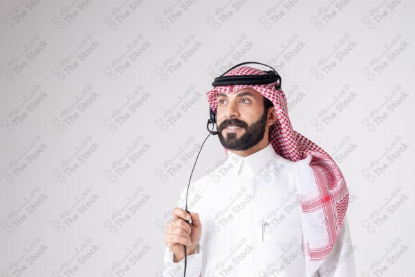 بورتريه رجل سعودي يلبس سماعة الرأس ويقوم بالتواصل عبر السماعة - خدمة العملاء ، مكالمة هاتفية