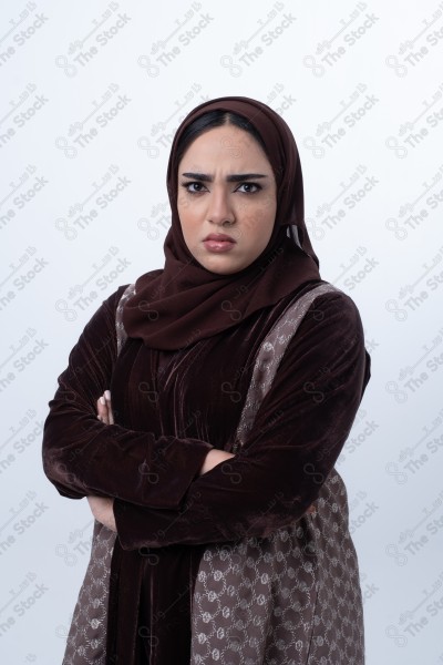 A young Saudi woman wearing an abaya and hijab, looking angry