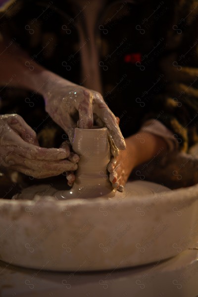 A Saudi girl wearing an abaya makes pottery in the workshop and shows her hand full of clay, a handicraft