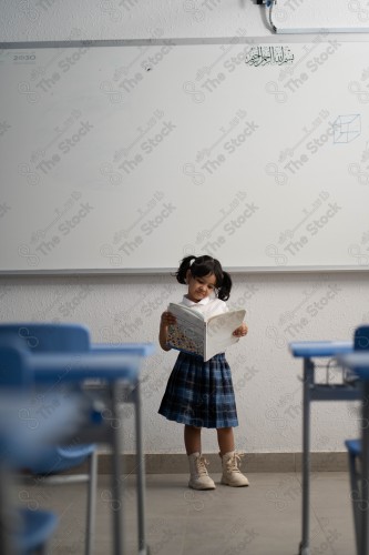 A Saudi student wears a school uniform and does different interactions and shows the tables in the classroom