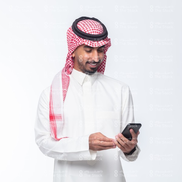 رجل سعودي يرتدي الزي السعودي الرسمي
 ويستخدم الجوال على خلفية بيضاء