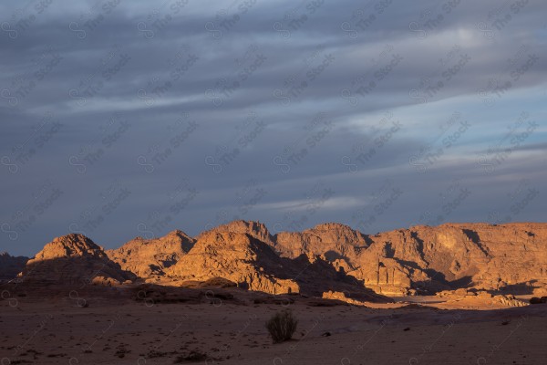 لقطة لشروق اشعة الشمس على جبال محافظة العلا التاريخية نهارًا، سلسلة من الجبال الصخرية.