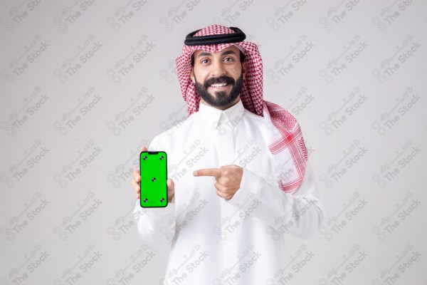 Portrait of a Saudi man holding a phone, pointing at the phone and making different expressions - green screen