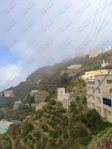 A group of houses on a mountain in Fifa Governorate surrounded by agricultural terraces during the day, nature in Saudi Arabia.