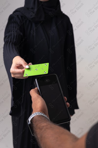 Portrait of a Saudi woman holding a card and making automatic payments on a white background