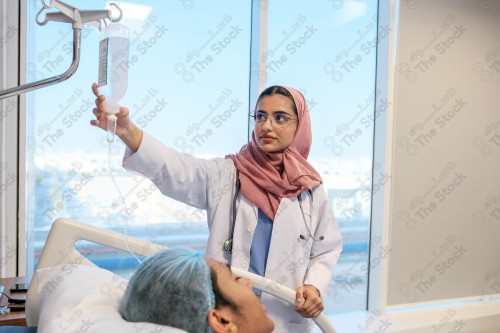 A Saudi female doctor wears a medical uniform and is examining and applying a nutrient solution, medicine and health care