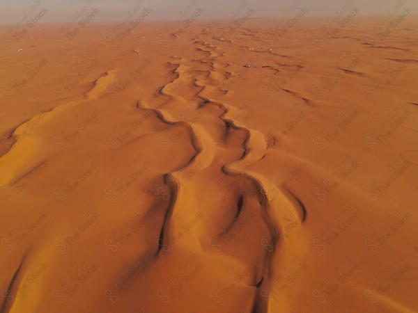 لقطة للكثبان الرملية الصحراوية بالسعودية وتبدو السماء شبة صافية ، الرمال الذهبية في صحراء السعودية ، الربع الخالي ، مناطق صحراوية