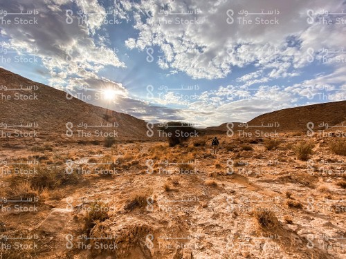 Sunshine and pieces of clouds over a man exploring lands in the Tuwaiq Mountains in Saudi Arabia