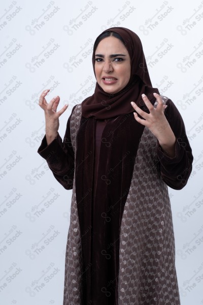 A young Saudi woman wearing an abaya and hijab, looking angry