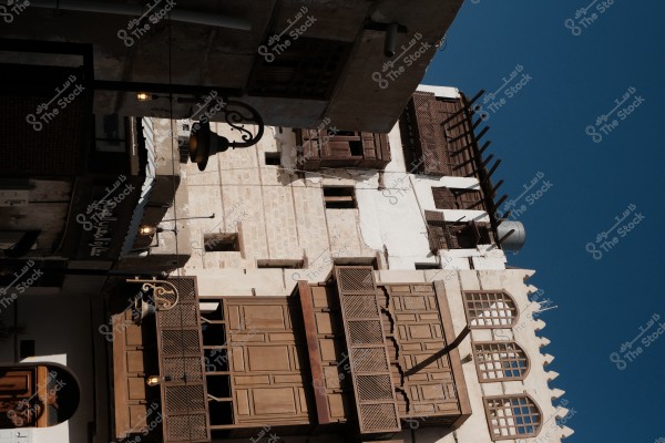 A traditional building in the old city of Jeddah, featuring old wooden windows and hanging lanterns.