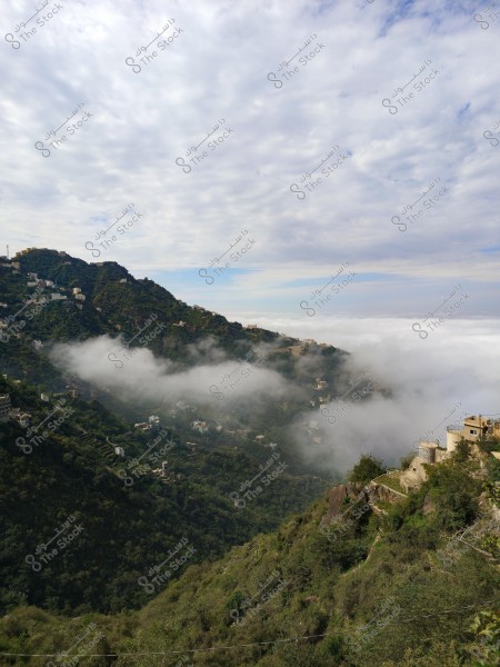 تُظهر الصورة منظرًا طبيعيًا لجبل مُغطى بالخُضرة والضباب, يمتد فوقه العديد من البيوت الصغيرة المبعثرة على السفوح. تحتل السماء نصف الصورة تقريبًا, مملوءة بالسحب التي تبعث على الشعور بالسلام. يبدو البناء في المقدمة مبنيًا على نمط تقليدي على حافة الجبل.