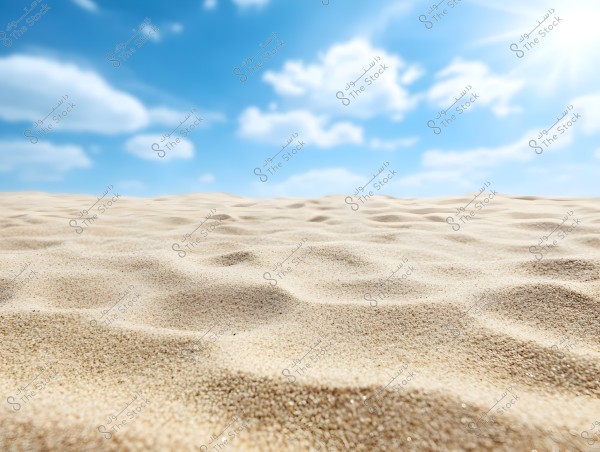 Image of a desert scene with soft sand in the foreground featuring gentle ripples. In the background, a wide blue sky is visible with scattered white clouds and bright sunlight.