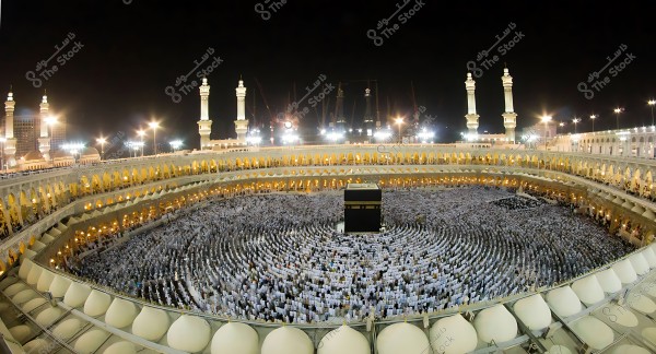 منظر علوي للمسجد الحرام في مكة المكرمة بالكعبة المشرفة محاطة بأعداد كبيرة من المصلين خلال الليل.