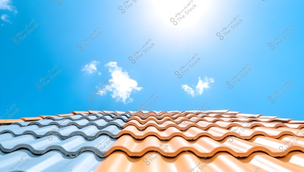 Image showing a roof covered with wavy orange and blue tiles under a clear blue sky with a few white clouds visible in the distance. The sun is shining brightly at the top of the image, creating a reflective effect on the tiles.