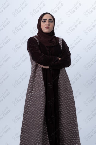 A young Saudi woman wearing an abaya and hijab, looking angry