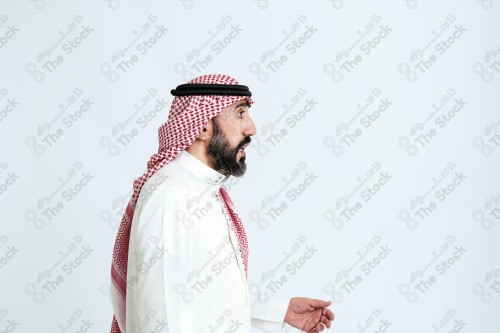 بورتريه رجل سعودي كبير بالسن يرتدي الزي الرسمي التقليدي على خلفية بيضاء يقوم بعمل اشارات بيديه وهو مبتسم ، حزين، غاضب، صور تذكارية ، توثيق لحظة سعيدة.