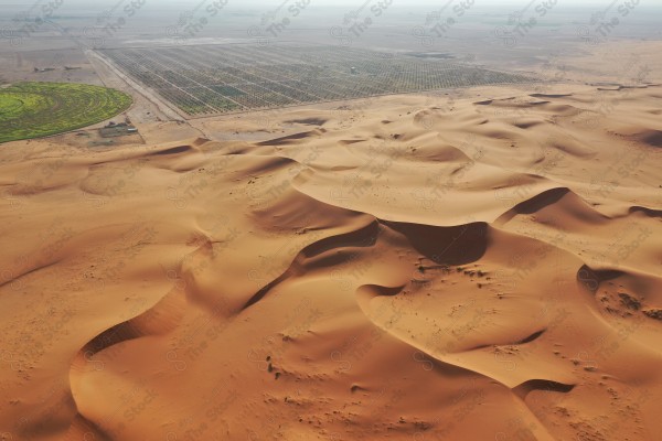 لقطة جمالية للكثبان الرملية الصحراوية بالسعودية وتظهر مزرعة في وسط الصحراء ، الرمال الذهبية في صحراء السعودية ، مناطق صحراوية .