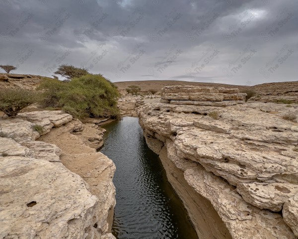 لقطة لاحد الاودية لسلسلة جبال طويق في منطقة نجد وتظهر السماء غائمة ، سلسلة من الجبال الصخرية ، تكوينات صخرية.