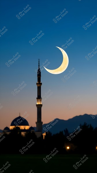 An image of a prominent mosque minaret under a shining crescent moon in the blue dawn sky. The mosque, with its dome and illuminated towers, is visible in the foreground, while mountains stretch across the background, adding a sense of beauty and tranquility to the scene.