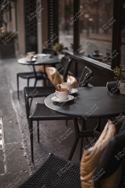 مقهى خارجي مع طاولات وكراسي فارغة وفناجين قهوة على الطاولة.