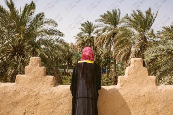 A snapshot of a Saudi man wearing folkloric costume on the day of the foundation stands over a mud building, heritage uniform, on the day of establishment, old archaeological buildings.