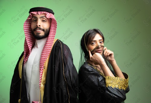 رجل سعودي يرتدي الزي السعودي وامرأه سعودية ترتدي المخنق والزي السعودي التقليدي الشعبي للمناسبات والإحتفالات الوطنية على خلفية خضراء